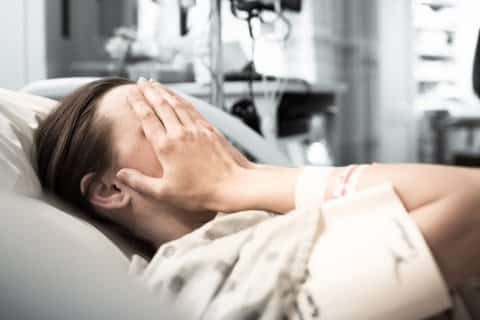 Weinende Frau liegt im Krankenhausbett