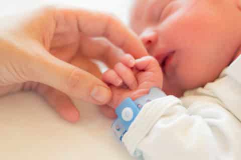 Neugeborenes Baby hält die Hand seiner Mutter