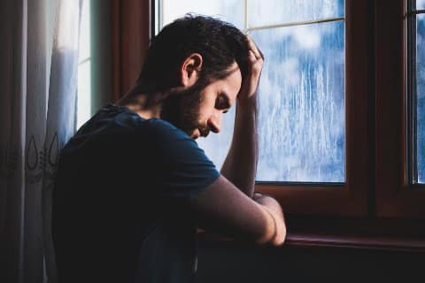 Erfahrungen - Spätabtreibung, auch der Vater leidet Verzweifelter Mann sitzt traurig an einem Fenster