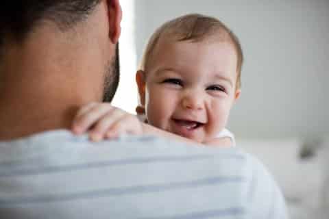 Kosten - Kinderbtreuungsgeld Mann hält lachendes Baby im Arm