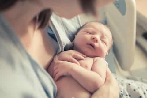 Kosten - Wochengeld Frau hält neugeborenes Baby in den Händen
