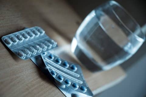 Methoden einer Abtreibung - Pille danach Pillen Verpackung auf einem Holztisch mit einem Wasserglas