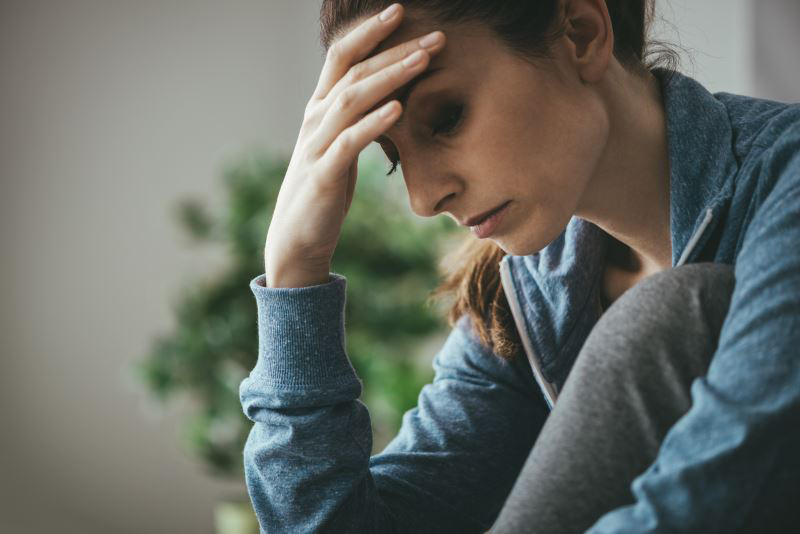 Risiken einer Abtreibung - Studienergbenisse Traurige Frau mit angewinkeltem Bein